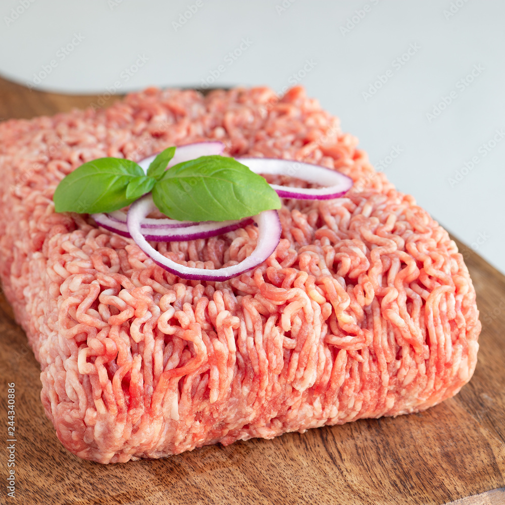 Minced meat from pork and beef. Ground meat with ingredients for cooking on wooden board, square format Minced meat from pork and beef. Ground meat with ingredients for cooking on wooden board, square format