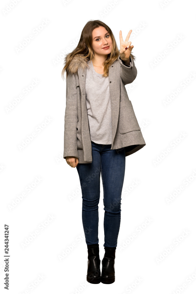 A full-length shot of a Teenager girl with coat smiling and showing victory sign on isolated white background A full-length shot of a Teenager girl with coat smiling and showing victory sign on isolated white background