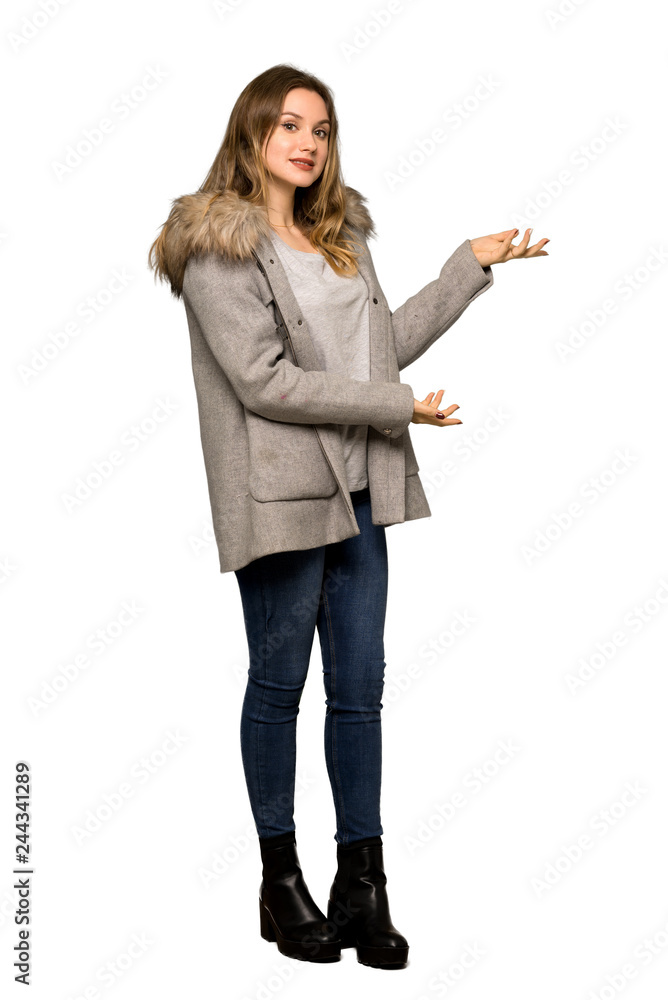A full-length shot of a Teenager girl with coat extending hands to the side for inviting to come on isolated white background A full-length shot of a Teenager girl with coat extending hands to the side for inviting to come on isolated white background