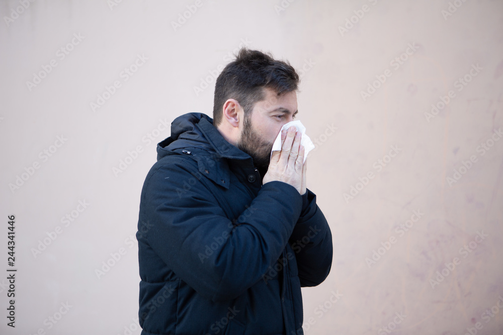 Man sneezing in winter with hanky in hand Man sneezing in winter with hanky in hand