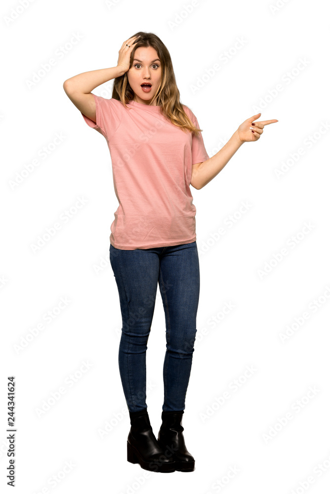 A full-length shot of a Teenager girl with pink sweater pointing with the index finger and looking up on isolated white background A full-length shot of a Teenager girl with pink sweater pointing with the index finger and looking up on isolated white background