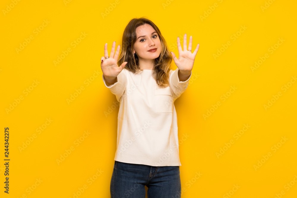 Teenager girl over yellow wall counting nine with fingers Teenager girl over yellow wall counting nine with fingers