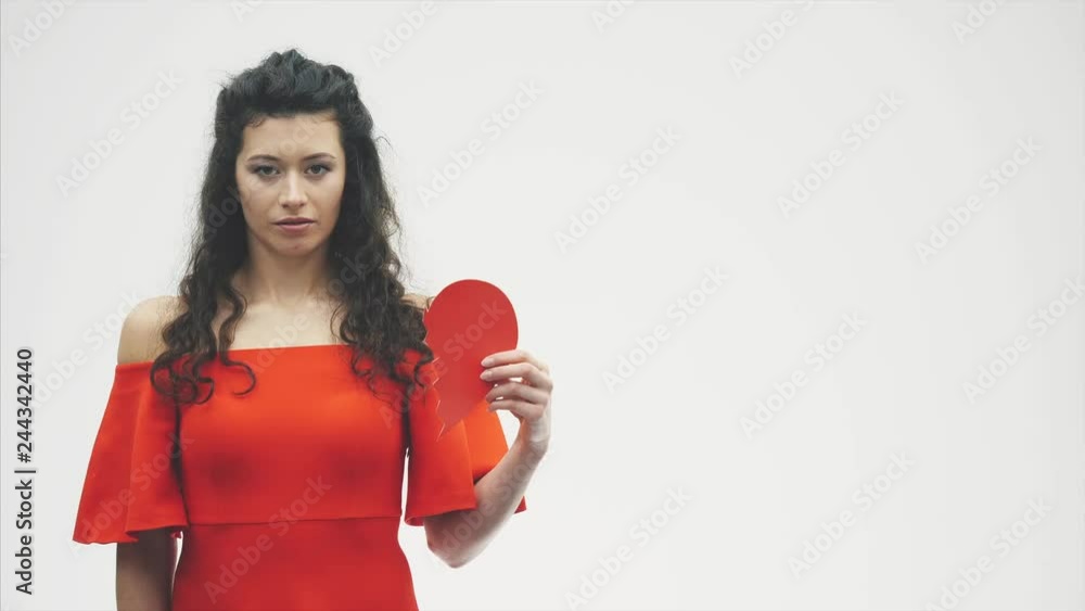 Portrait of a beautiful woman on a white background. Bad Valentine's Day. The concept, the model holds a red broken heart in its hands. Portrait of a beautiful woman on a white background. Bad Valentine's Day. The concept, the model holds a red broken heart in its hands.