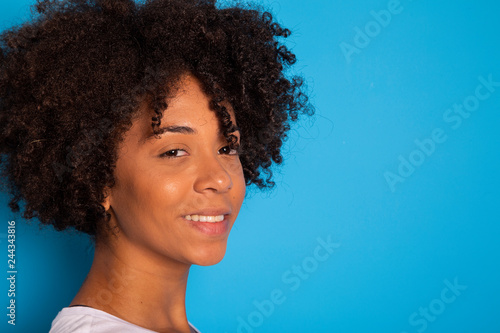 Portrait of cool young black woman laughing against blue wall - Imagem
