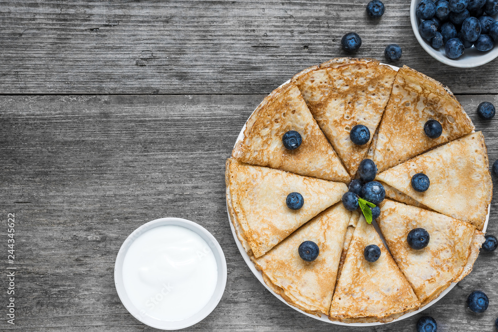 Stack of pancakes or crepes with fresh blueberry, sour cream and mint. Top view with copy space Stack of pancakes or crepes with fresh blueberry, sour cream and mint. Top view with copy space