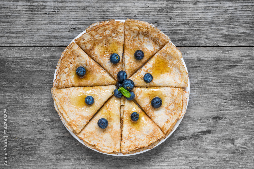 Stack of pancakes or crepes with fresh blueberry, maple syrup and mint. Top view