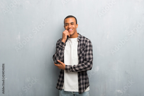 Young african american man with checkered shirt smiling with a sweet expression