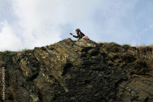 young woman taking selfies with the landscape on the edge of the cliff