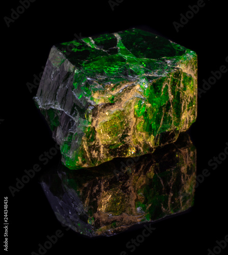 Crystal of natural green chrome diopside on black background with reflection