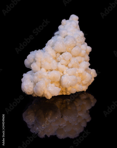 Natural druse of white calcite on a black background with reflection