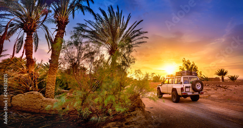 Travel, SUV rides a desert road at beautiful sunset, extreme travel adventure in nature