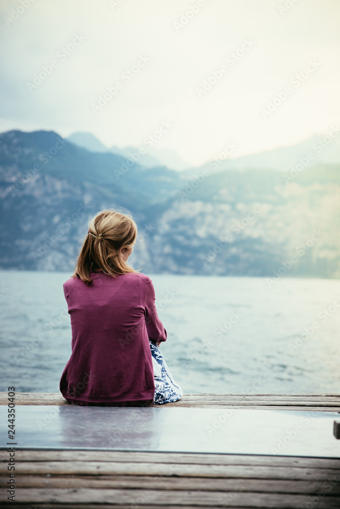 Beautiful young woman is sitting on a footbridge and enjoying the view, vacation Beautiful young woman is sitting on a footbridge and enjoying the view, vacation