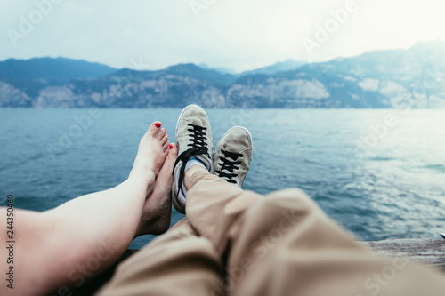 Boy and girl are enjoying their holiday evening: Sneakers and barefoot feet, lake and mountains photo