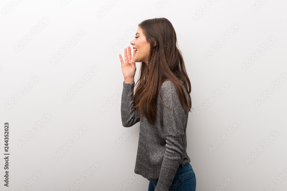 Teenager girl on isolated white backgorund shouting with mouth wide open to the lateral Teenager girl on isolated white backgorund shouting with mouth wide open to the lateral