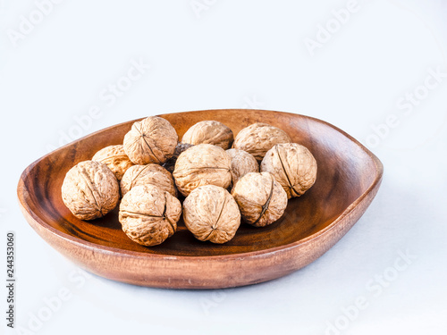 Some nuts on the wooden plate and white background