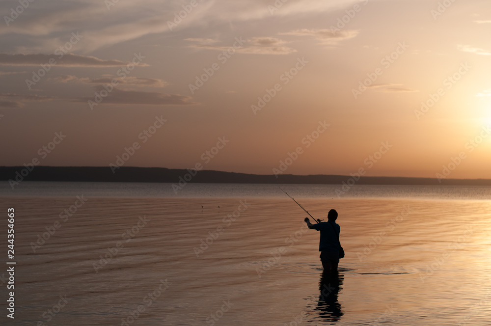 Fototapeta premium silhouette of man on the beach at sunset, fisherman