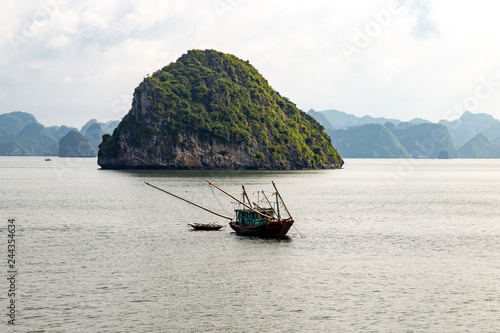 A local fisherman boat among the karst formations in Halong Bay, Vietnam, in the gulf of Tonkin. Halong Bay is a UNESCO World Heritage Site and the most popular tourist spot in Vietnam