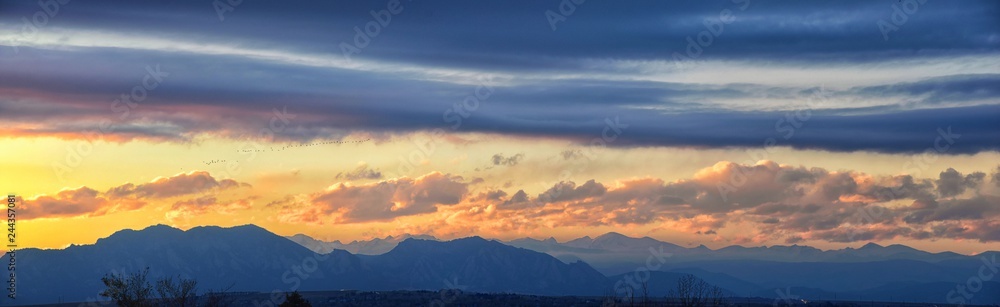 Tranquil panoramia scene of red sun and orange sky sunset over the Rocky Mountains in Colorado by Denver, United States.