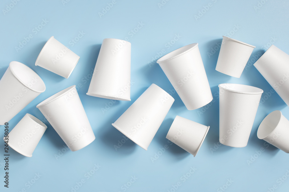 White disposable cups on the light blue background - obrazy, fototapety, plakaty 