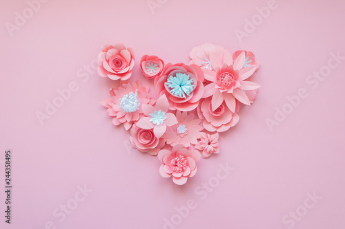 Heart from rose paper flowers on pink background. Cut from paper.