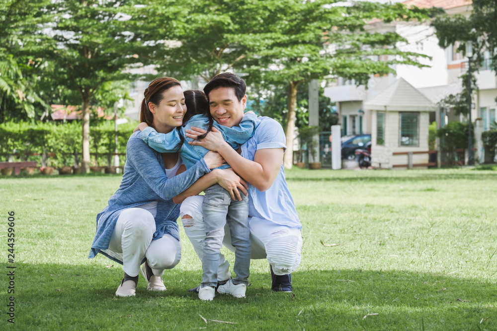 Happy Asian family playing with daughter girl in green garden