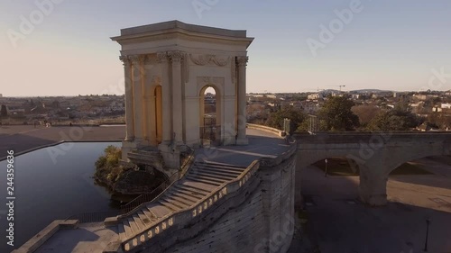 Beautiful sunlight flare flying over water tower in Montpellier Peyrou parc aerial drone shot