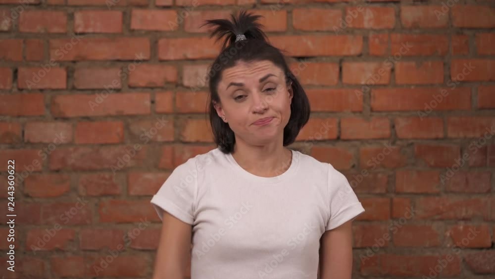 Close-up of a young disappointed woman doing facepalm while standing isolated against a brick wall background. Close-up of a young disappointed woman doing facepalm while standing isolated against a brick wall background.