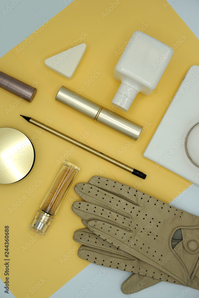 Flat lay composition of beauty products and handbag for women. Pastel and gold colors on gold background. Top view. Flat lay composition of beauty products and handbag for women. Pastel and gold colors on gold background. Top view.