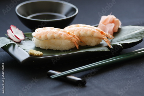Nigiri sushi with shrimp and tuna fish on a gourmet platting on black background. Sushi and chopsticks.