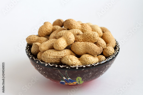 raw peanuts in shell on clay cup on white background