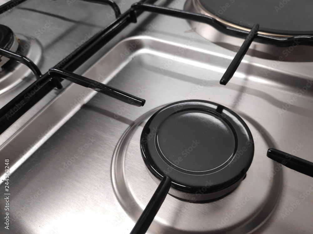 Gas burners on stainless steel gas fired freestanding hob. In the image can be seen the burner caps together with the burner body and cast iron pan support Gas burners on stainless steel gas fired freestanding hob. In the image can be seen the burner caps together with the burner body and cast iron pan support