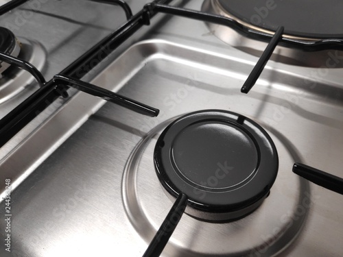 Gas burners on stainless steel gas fired freestanding hob. In the image can be seen the burner caps together with the burner body and cast iron pan support