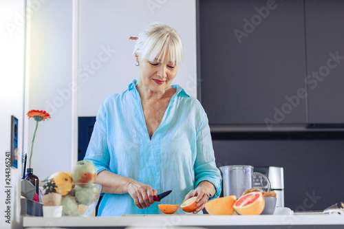 Positive aged woman looking at the orange