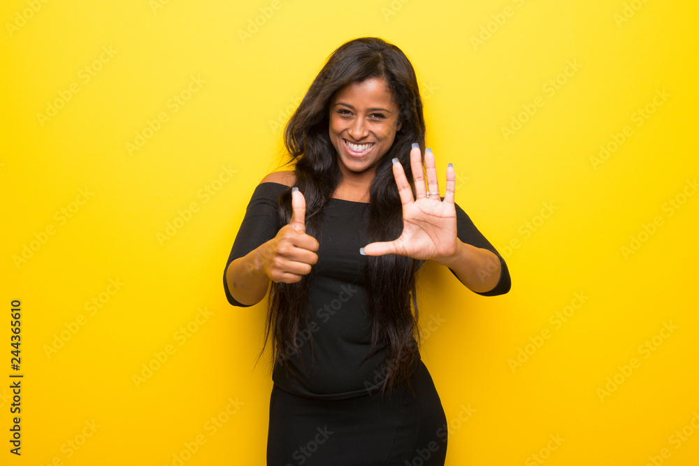 Young afro american woman on vibrant yellow background counting six with fingers Young afro american woman on vibrant yellow background counting six with fingers