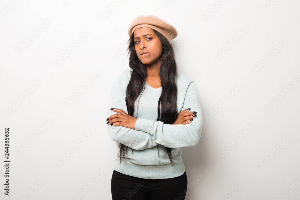 Young afro american woman on white wall having doubts and with confuse face expression while bites lip Young afro american woman on white wall having doubts and with confuse face expression while bites lip