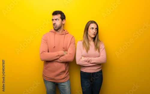 Group of two people on yellow background with confuse face expression while bites lip