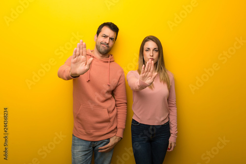 Group of two people on yellow background making stop gesture denying a situation that thinks wrong