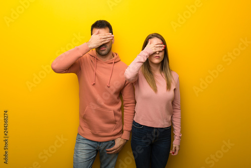 Group of two people on yellow background covering eyes by hands. Do not want to see something