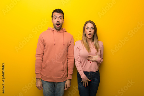 Group of two people on yellow background with surprise and shocked facial expression