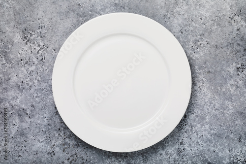 White empty ceramic plate on a stone table, top view. Food background
