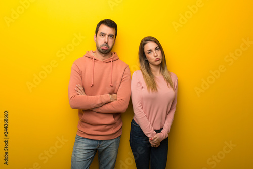 Group of two people on yellow background with sad and depressed expression © luismolinero