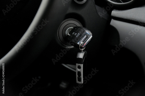 Car key and black dashboard with selective focus. Modern digital car panel with red arrow on blurred speedometer. Luxury automobile interior with control panel and key. Car details inside.