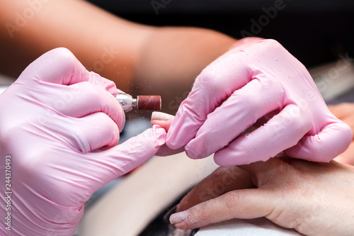 Closeup shot of hardware manicure in a beauty salon. Manicure process  cleaning of nails by a milling cutter. Procedure for the preparation of nails before applying nail polish.
