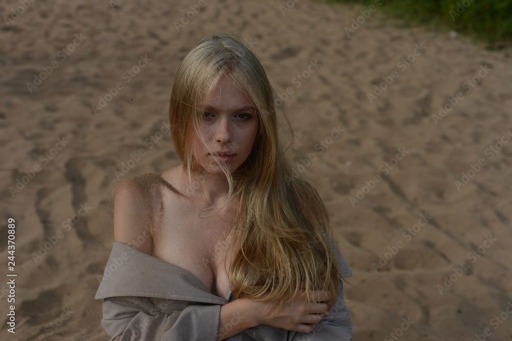 girl in a beige raincoat lying on the sand girl in a beige raincoat lying on the sand
