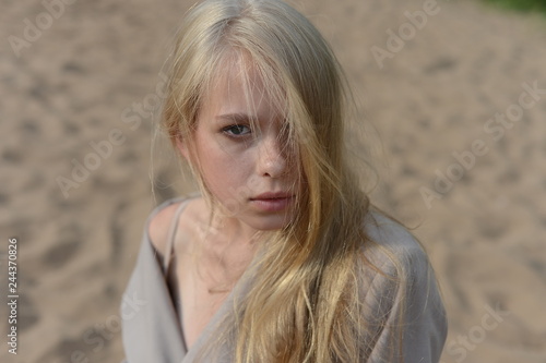girl in a beige raincoat lying on the sand © korotkovkris