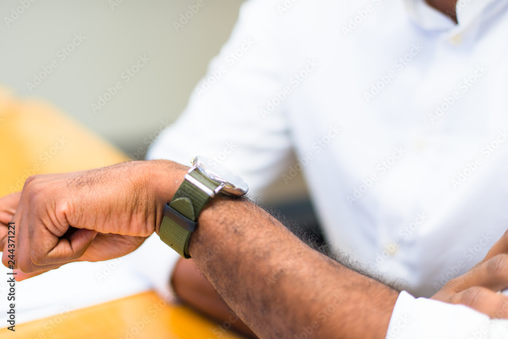 Detail of afro american businessman in the office looking dthe watch