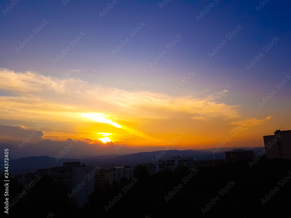 sunset scene with sun fall behind the clouds and mountains in background