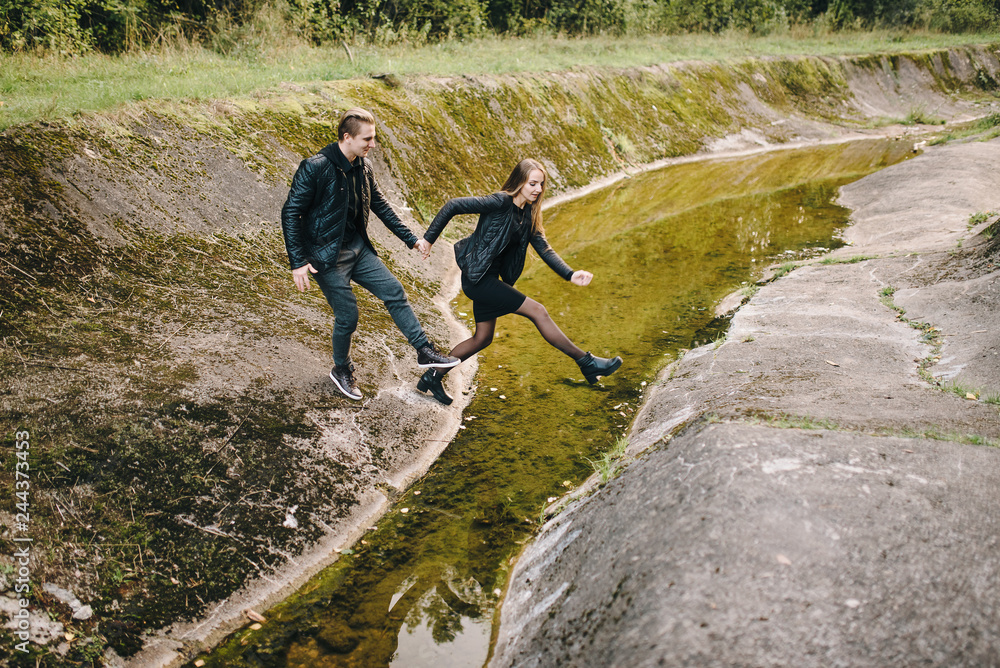 Obraz premium Young couple jumping over stream