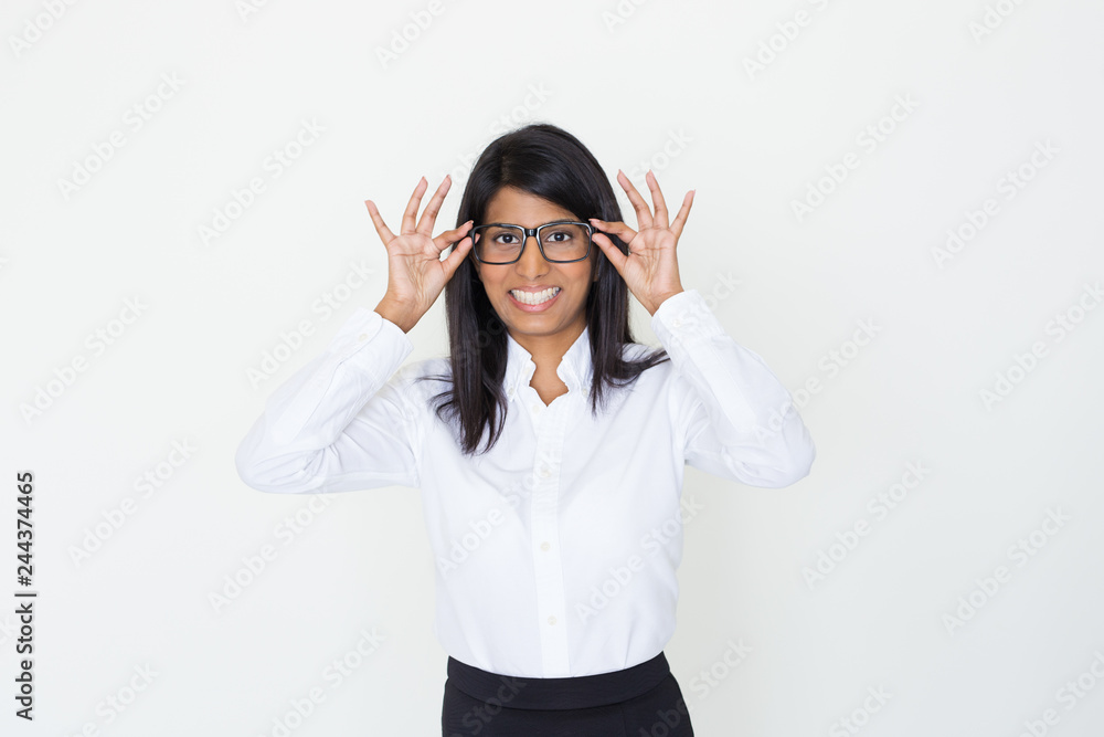 Happy positive office girl putting on eyeglasses. Beautiful Indian woman touching or taking off eyewear. Glasses wearing concept Happy positive office girl putting on eyeglasses. Beautiful Indian woman touching or taking off eyewear. Glasses wearing concept