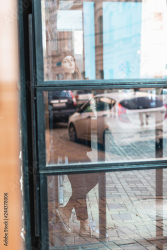 street photo of a girl with dreadlocks behind a glass door